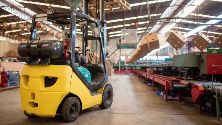 An operator demonstrating how to drive a forklift safely in a busy warehouse.